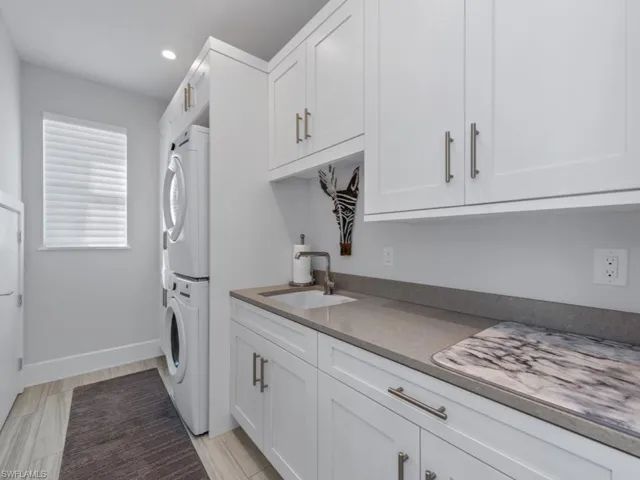 Kitchen featuring white cabinets, sink, and stacked washer and clothes dryer