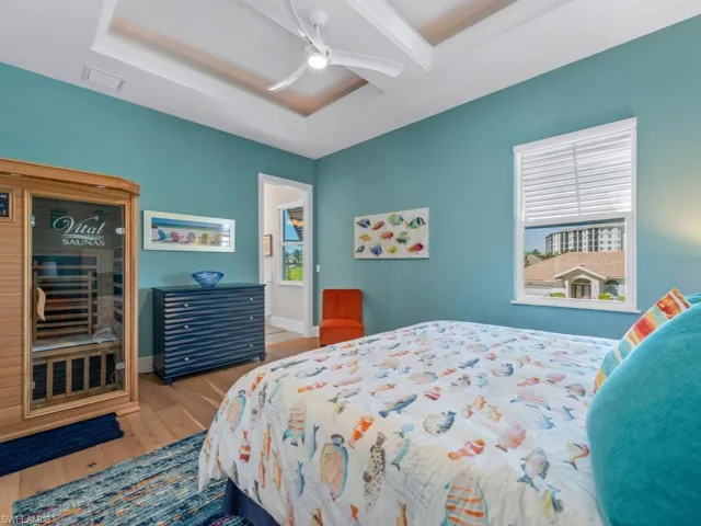 Bedroom with a tray ceiling, ceiling fan, and wood-type flooring