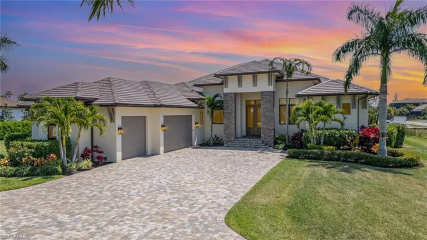 Custom executive home with a garage, a lawn, decorative driveway, stucco siding, and a tiled roof