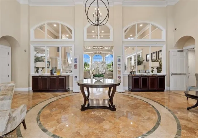 Grand foyer featuring high ceilings, polished stone flooring with circular inlay, arched transom windows, and an oversized spherical chandelier