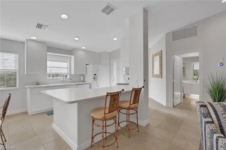 Kitchen featuring white cabinetry, solid-surface countertops, recessed lighting, and tile flooring