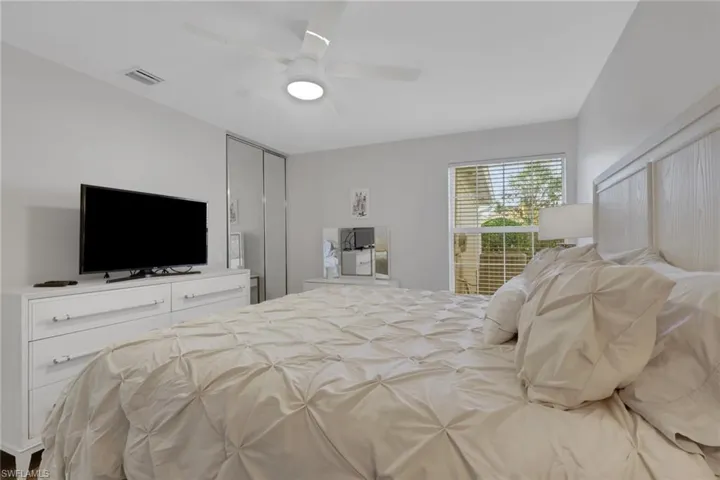 Room featuring a ceiling fan with integrated lighting, mirrored closet doors, and natural light via a single-pane window