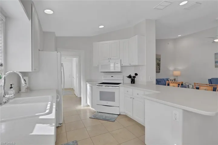 Kitchen featuring white cabinetry, solid-surface countertops, tile flooring, recessed lighting, and a breakfast bar