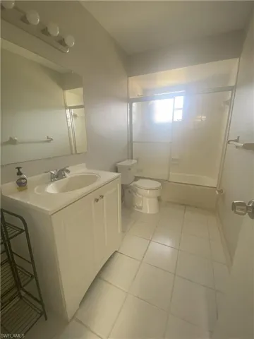 Bathroom with vanity, light tile patterned floors, and combined bath / shower with glass door