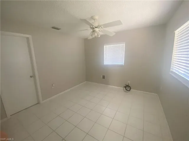 Unfurnished room with a textured ceiling, light tile patterned floors, and a ceiling fan