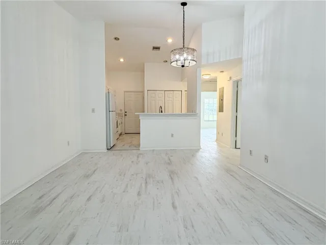 Unfurnished living room featuring light hardwood / wood-style flooring and a notable chandelier