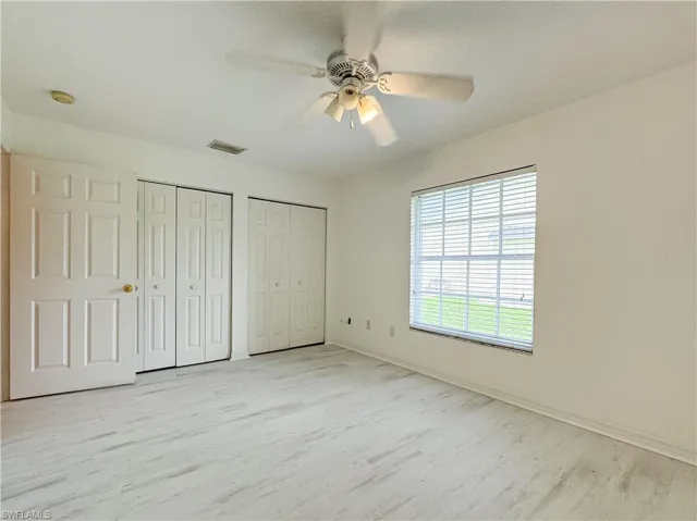 Unfurnished bedroom featuring ceiling fan, light wood-type flooring, and multiple closets