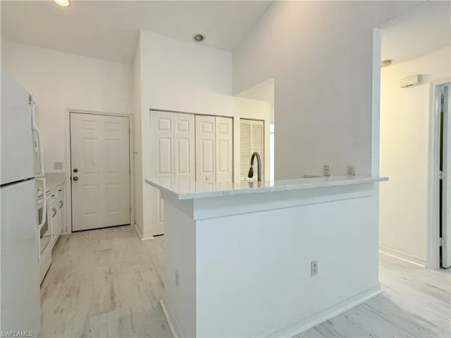 Kitchen featuring sink, kitchen peninsula, light hardwood / wood-style flooring, and white refrigerator