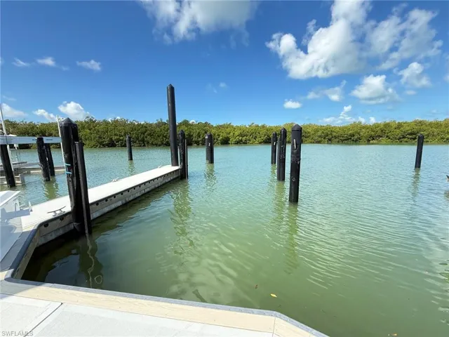 Waterfront property featuring a private boat dock, dark pilings, and calm water
