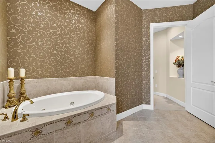 Bathroom featuring wallpapered walls, a whirlpool tub, and light tile patterned floors