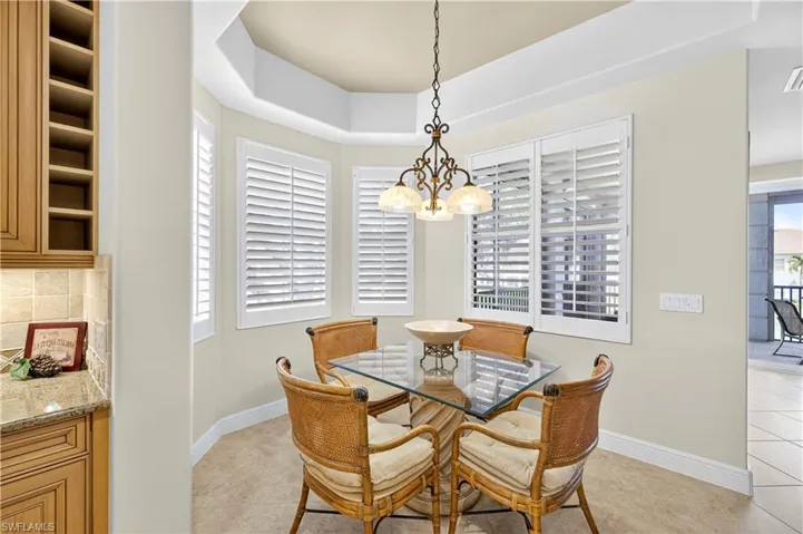Dining room featuring light tile patterned flooring, a raised ceiling, and a chandelier