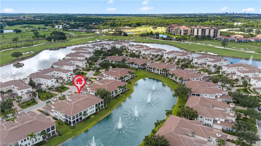 Aerial view of residential area featuring a golf course and a nearby body of water