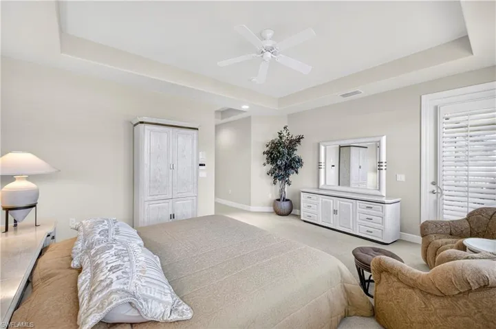 Bedroom featuring a raised ceiling, carpet flooring, and ceiling fan
