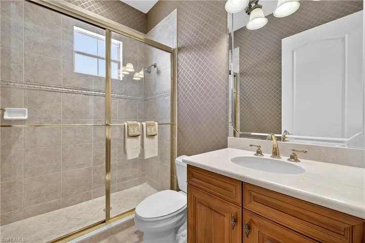 Full bathroom with vanity, a shower stall, and wallpapered walls