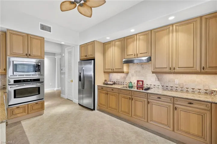 Kitchen with appliances with stainless steel finishes, backsplash, light stone countertops, ceiling fan, and recessed lighting