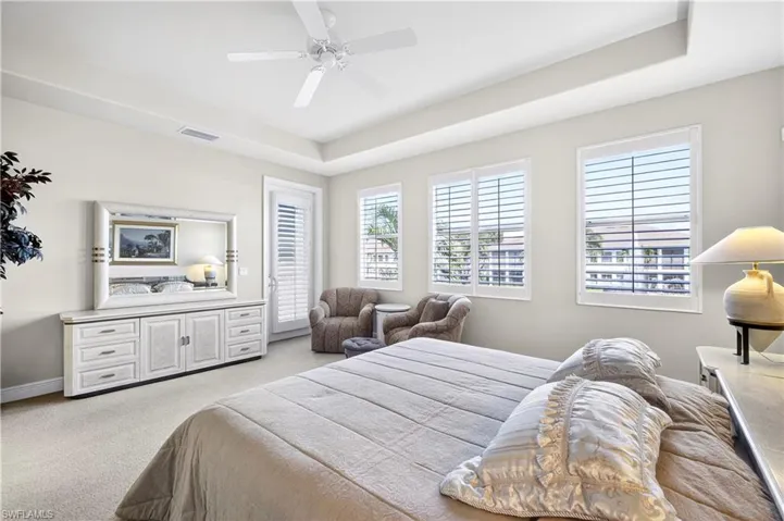 Bedroom featuring light colored carpet, ceiling fan, and a tray ceiling