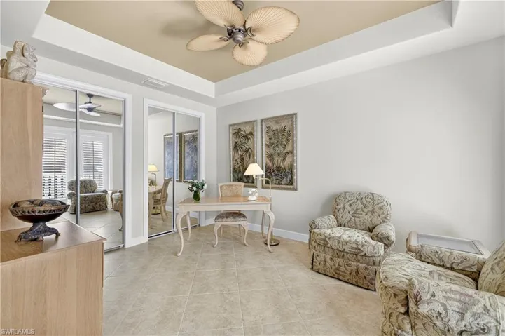 Office space featuring a raised ceiling, light tile patterned flooring, and a ceiling fan