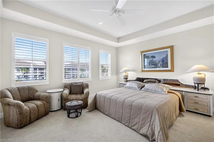 Bedroom featuring light carpet, a ceiling fan, and a tray ceiling