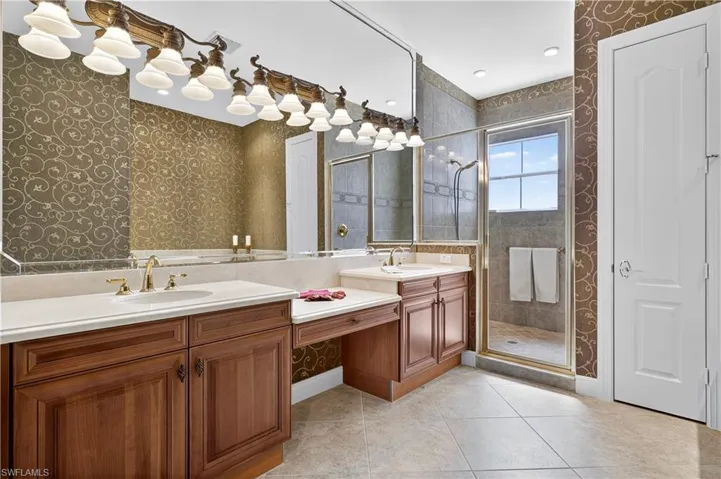 Bathroom with wallpapered walls, light tile patterned floors, a stall shower, double vanity, and a closet