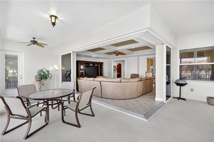 Carpeted dining area with healthy amount of natural light, coffered ceiling, beamed ceiling, ceiling fan, and tile patterned flooring