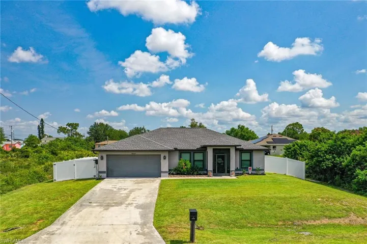 View of front of house featuring stucco siding, an attached garage, driveway, and a gate