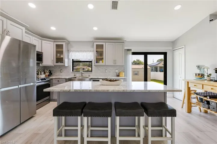 Kitchen featuring stainless steel appliances, a sink, a kitchen bar, healthy amount of natural light, and recessed lighting