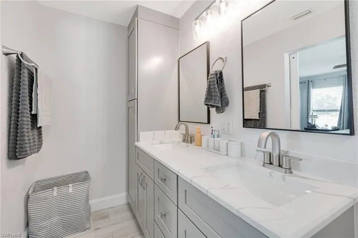 Full bath featuring double vanity and baseboards