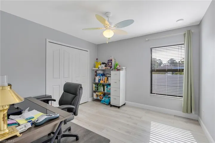 Home office featuring a ceiling fan, light wood-style floors, and baseboards