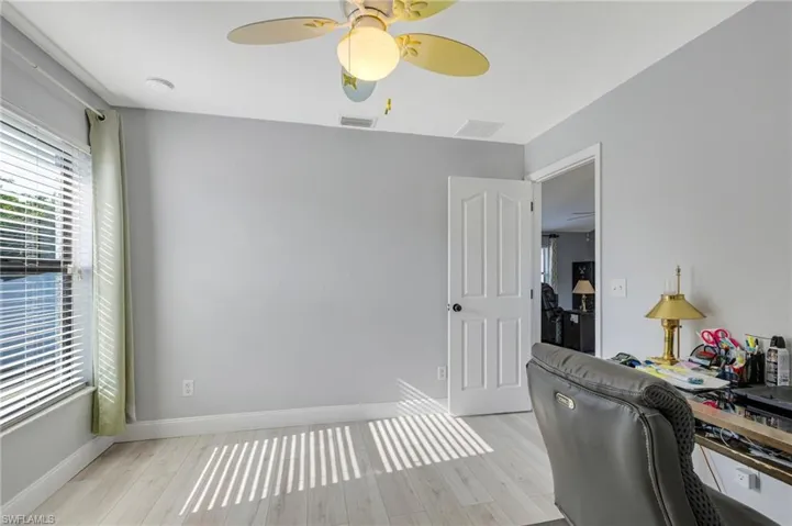 Home office featuring light wood-type flooring, a ceiling fan, and baseboards