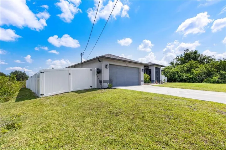 View of front of home with concrete driveway, a garage, stucco siding, and a gate