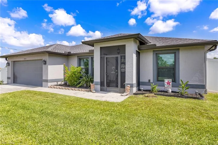 View of front of property featuring stucco siding, a garage, a front lawn, and concrete driveway