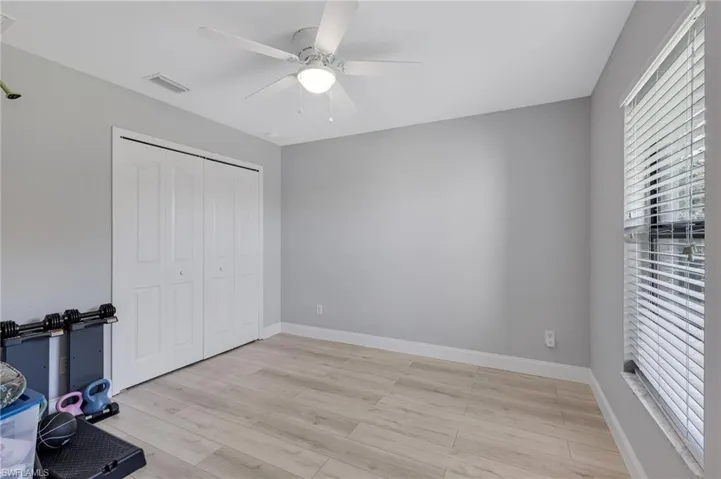 Unfurnished bedroom with light wood finished floors, a closet, baseboards, and a ceiling fan