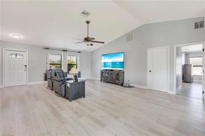 Living area featuring ceiling fan, plenty of natural light, light wood-style floors, and high vaulted ceiling