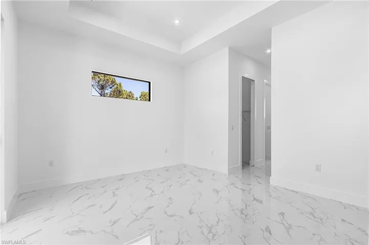 Unfurnished room with light marble finish flooring, a tray ceiling, and recessed lighting
