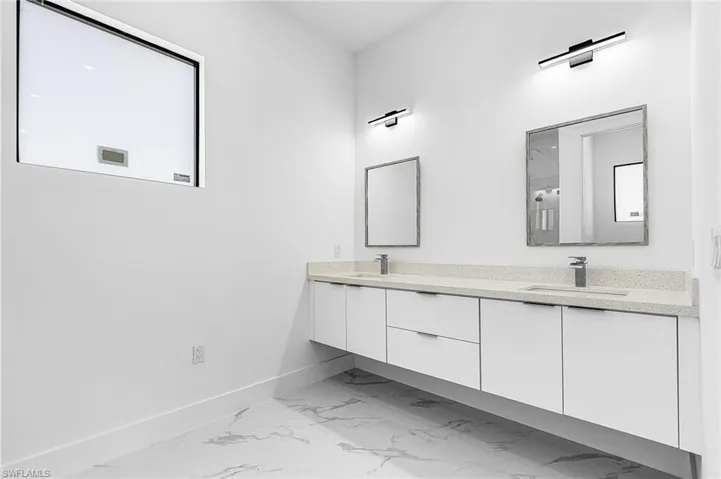 Full bathroom with double vanity and light marble finish floors