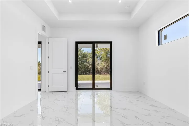 Unfurnished room with a tray ceiling and light marble finish floors