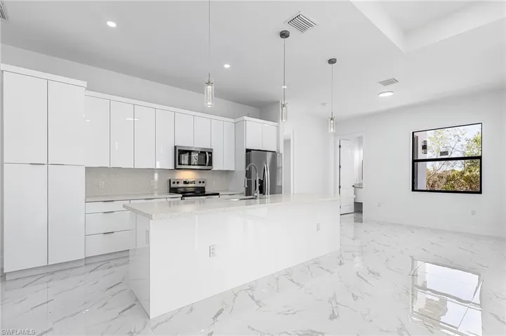 Kitchen with pendant lighting, white cabinetry, stainless steel appliances, and modern cabinets