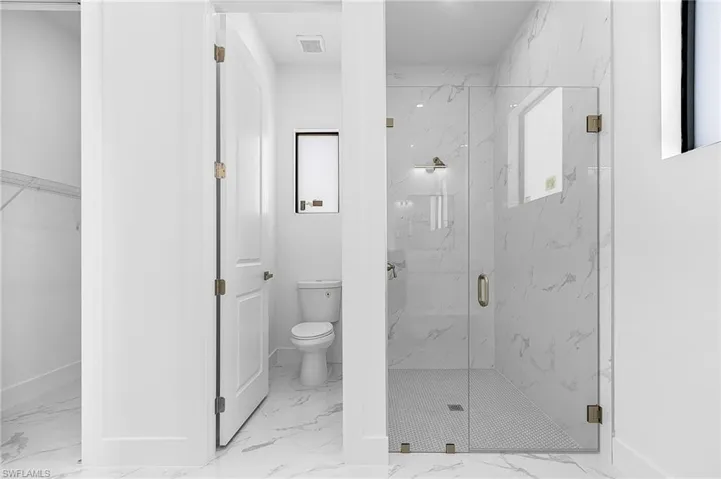 Bathroom featuring a marble finish shower and a spacious closet