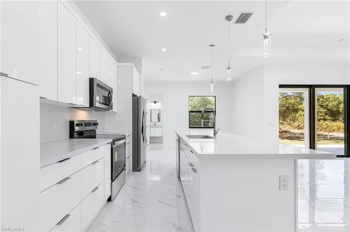 Kitchen featuring stainless steel appliances, white cabinets, modern cabinets, and a center island with sink
