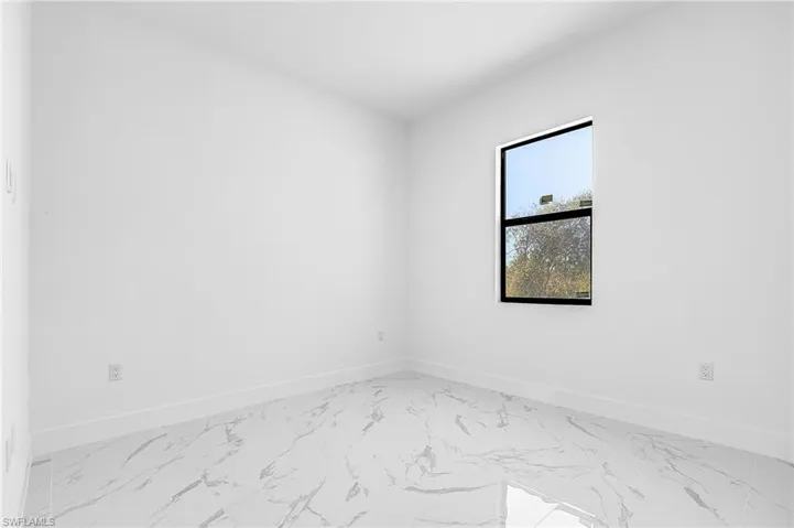 Unfurnished room featuring baseboards and light marble finish flooring