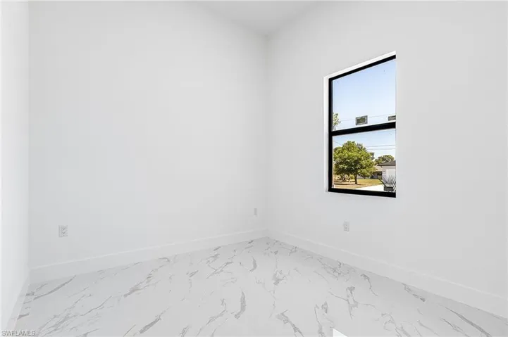 Unfurnished room featuring baseboards and light marble finish floors
