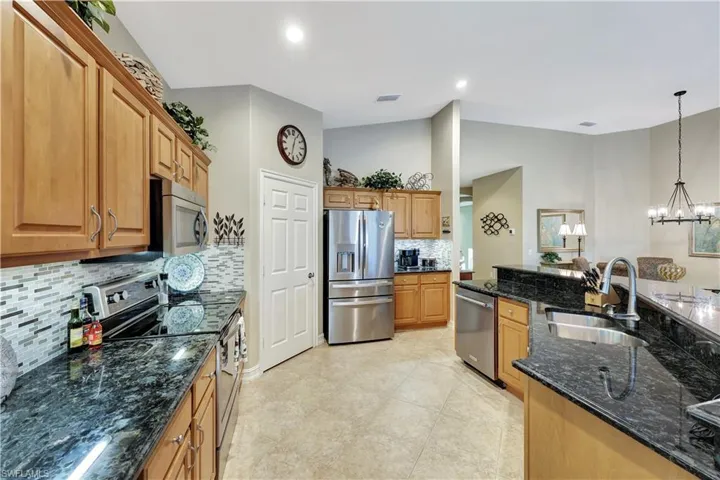 Kitchen featuring pendant lighting, appliances with stainless steel finishes, sink, tasteful backsplash, and dark stone countertops