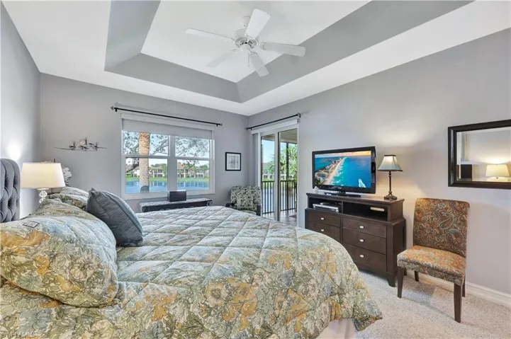 Bedroom featuring ceiling fan, a raised ceiling, access to outside, and light carpet