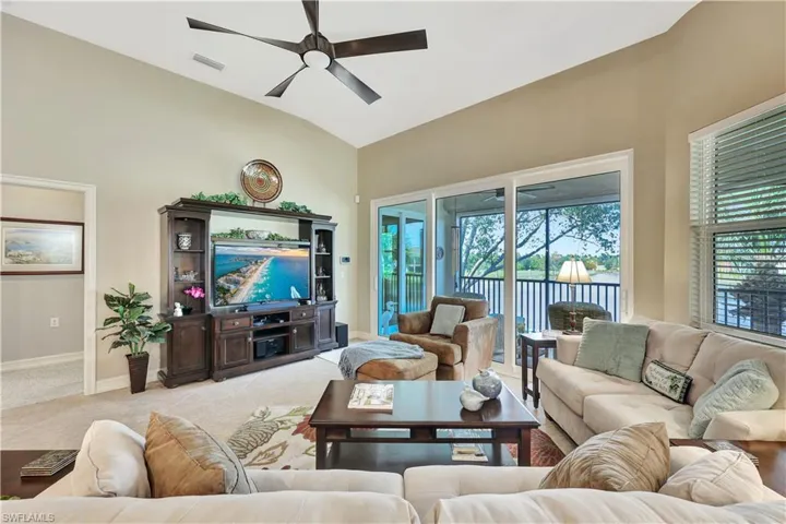 Carpeted living room featuring ceiling fan and lofted ceiling