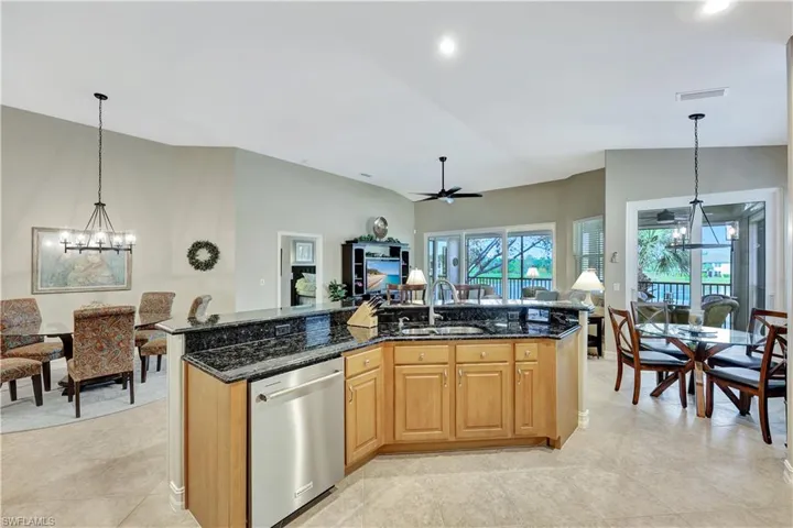 Kitchen featuring sink, stainless steel dishwasher, lofted ceiling, and dark stone countertops