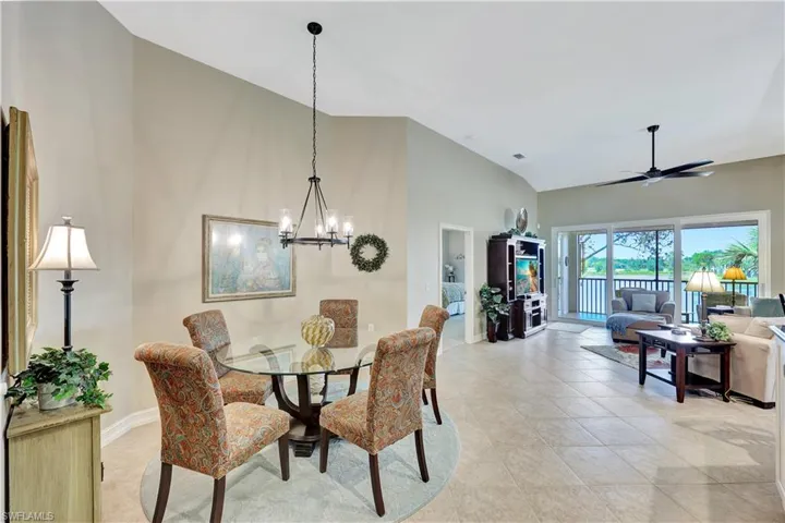 Tiled dining space with ceiling fan with notable chandelier and vaulted ceiling