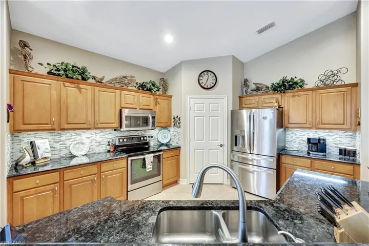 Kitchen with sink, dark stone countertops, and stainless steel appliances