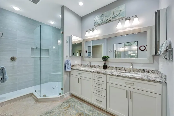 Bathroom with a shower with shower door, tile patterned floors, and vanity