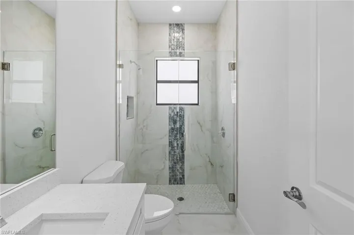 Bathroom featuring tile floors, walk in shower, toilet, and large vanity