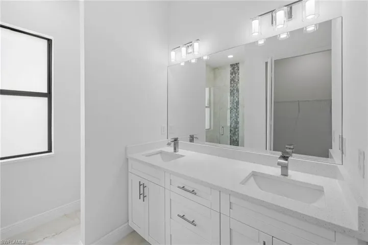 Bathroom with vanity with extensive cabinet space, an enclosed shower, dual sinks, and tile flooring
